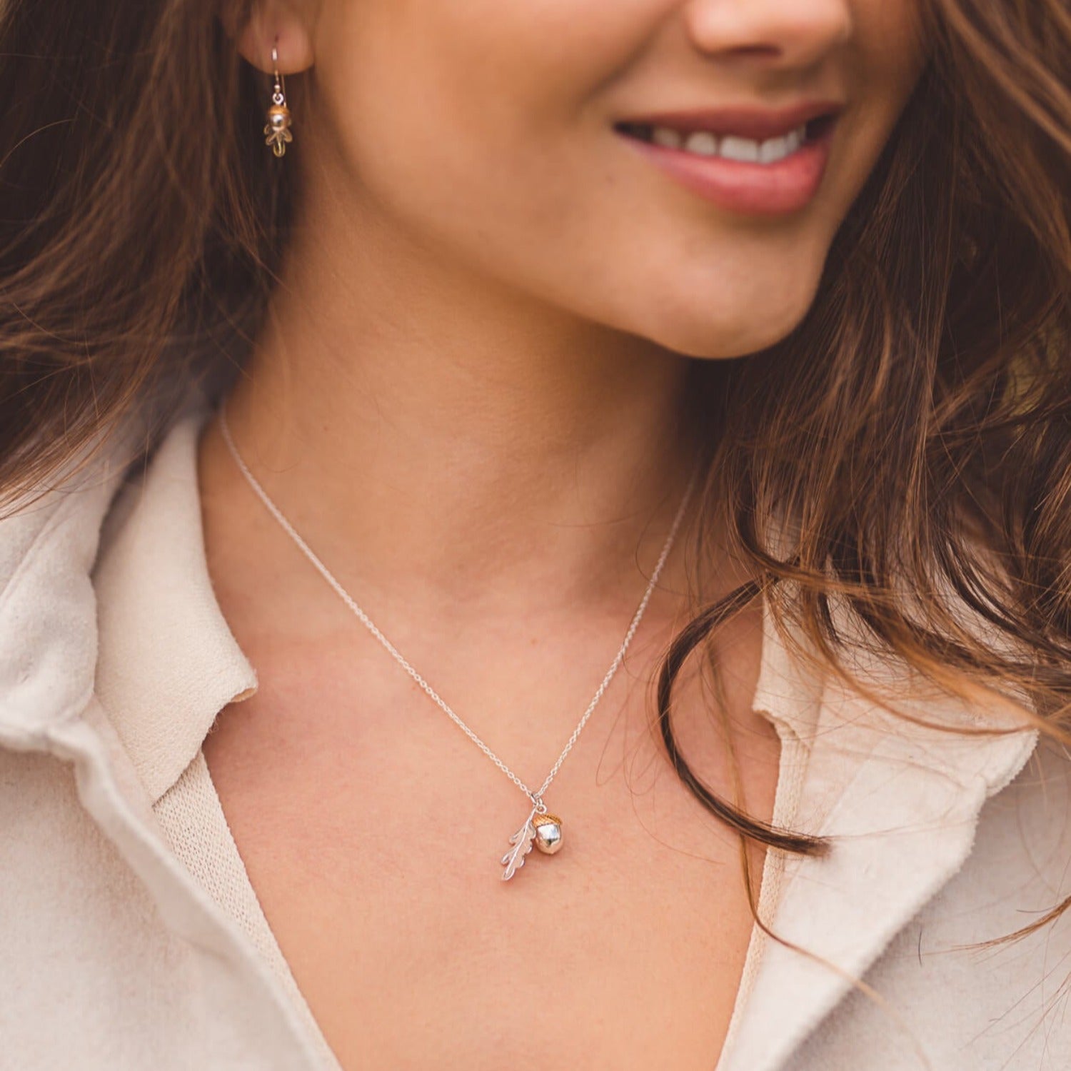 A Sterling Silver and Gold Plate Oak Leaf and Acorn Pendant, hanging on a silver adjustable chain and worn on a model with the matching drop earrings.
