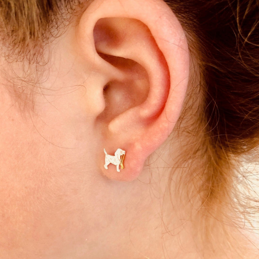 A sterling silver dog stud with a hammered finish, holding an 18ct gold plate lead in its mouth and shown in a ladies ear.