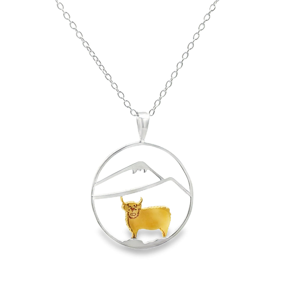 A sterling silver circular pendant with an 18ct gold plated highland cow with silver hills inside the circle. The pendant hangs from a sterling silver adjustable chain.