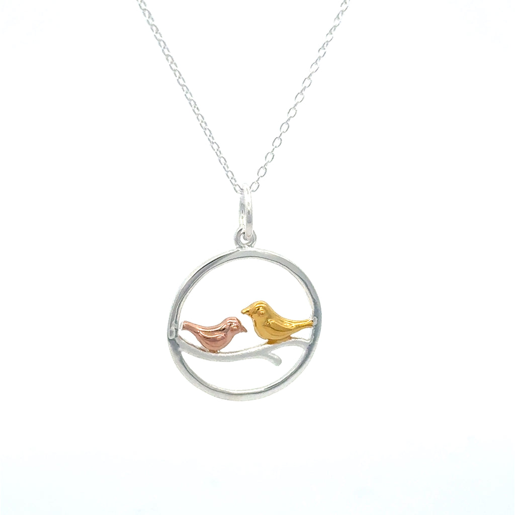 Necklace with a circular pendant featuring two birds in gold and rose gold plate sat on a branch in the centre of the circle. Hanging on a silver adjustable chain.