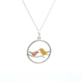 Necklace with a circular pendant featuring two birds in gold and rose gold plate sat on a branch in the centre of the circle. Hanging on a silver adjustable chain.