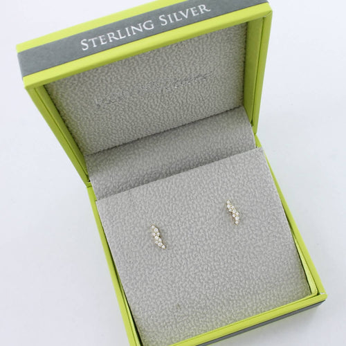 A pair of sterling silver and 18ct gold plated stud earrings in a lightening strike shape, filled with cubic zirconia stones. The studs are shown in a Reeves & Reeves branded gift box.