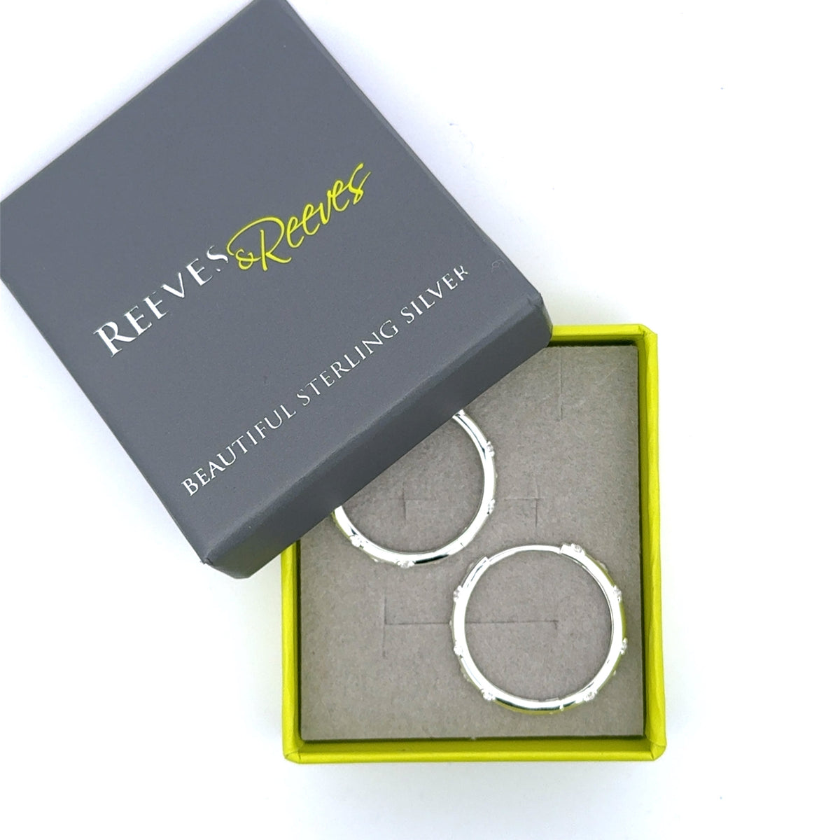 A pair of sterling silver hoop earrings with moissanites set in the hoop. Shown in a Reeves & Reeves gift box.