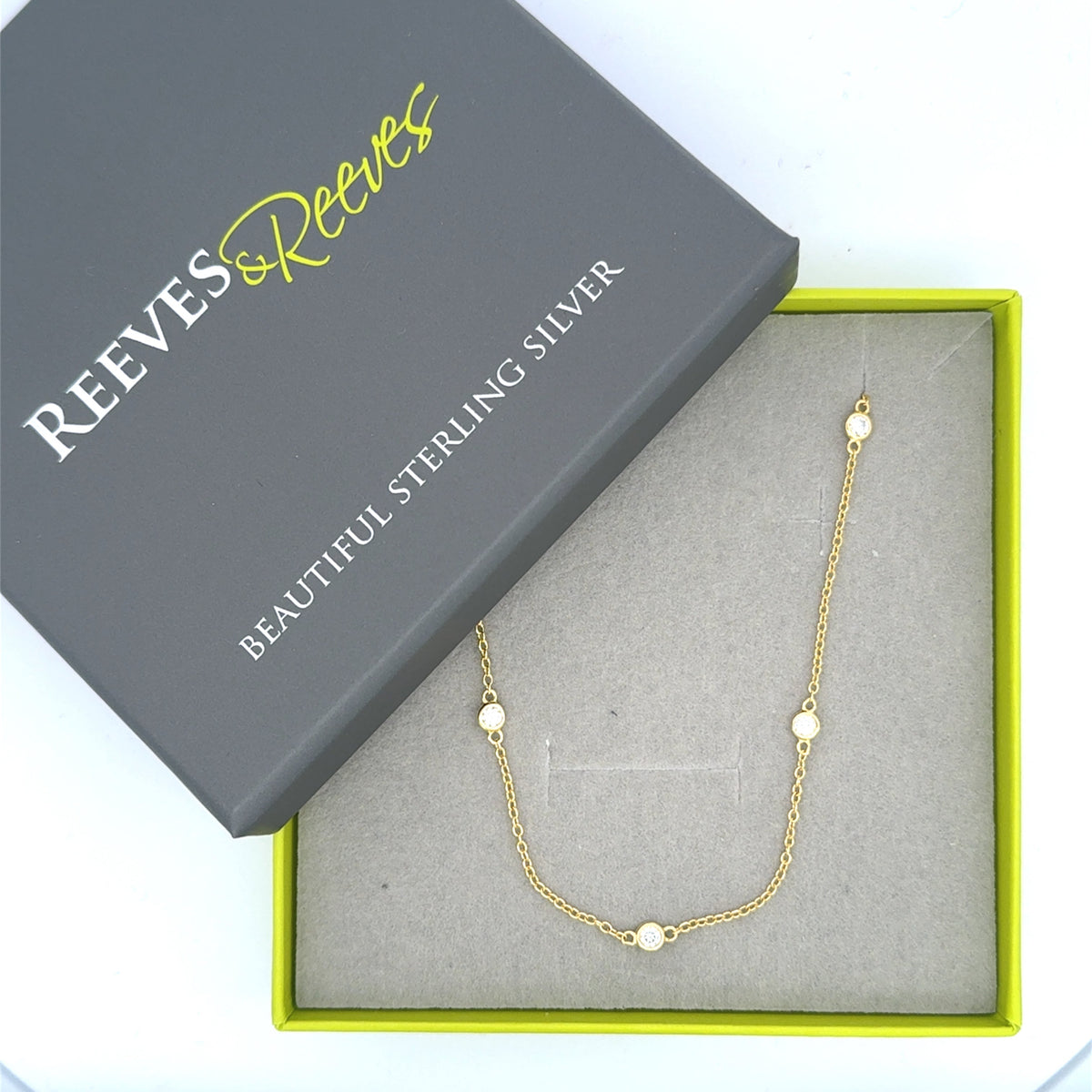 A silver and gold plated necklace with moissanites set along the fine chain. Shown in a Reeves & Reeves gift box.