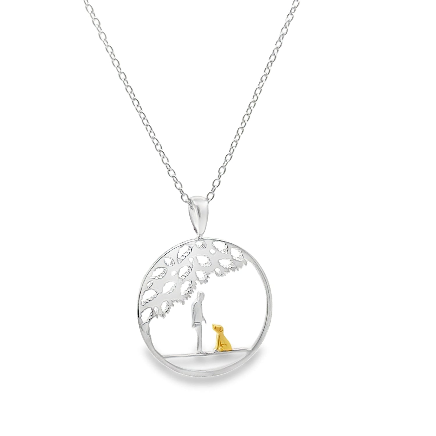 A sterling silver circular necklace with a tree design inside, and a silhouette of a person with an 18ct gold plated dog sat beneath the tree. The pendant hangs on a silver adjustable chain.