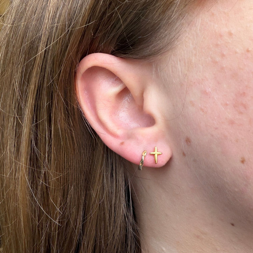 gold plated little kiss studs, worn in a ladies ear with a pair of simple gold huggies.