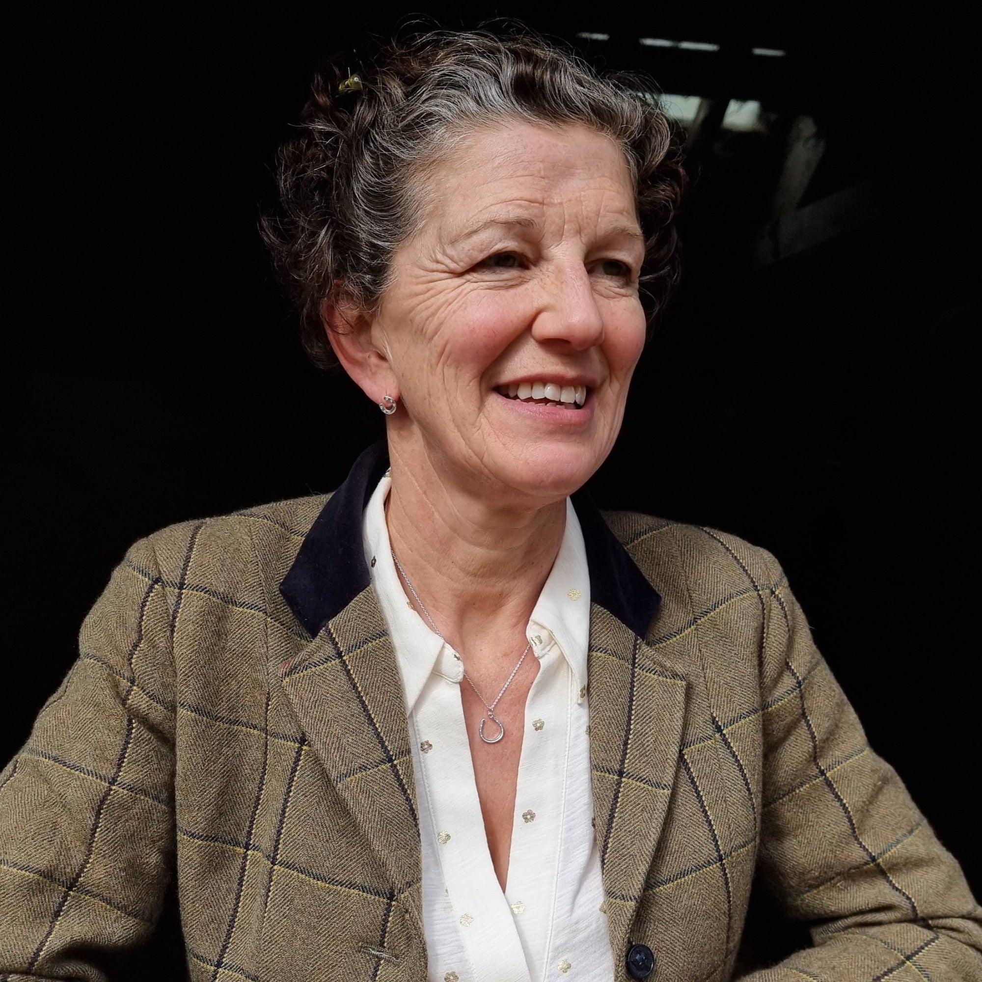A Sterling Silver Horseshoe Necklace worn on a model in a stable.