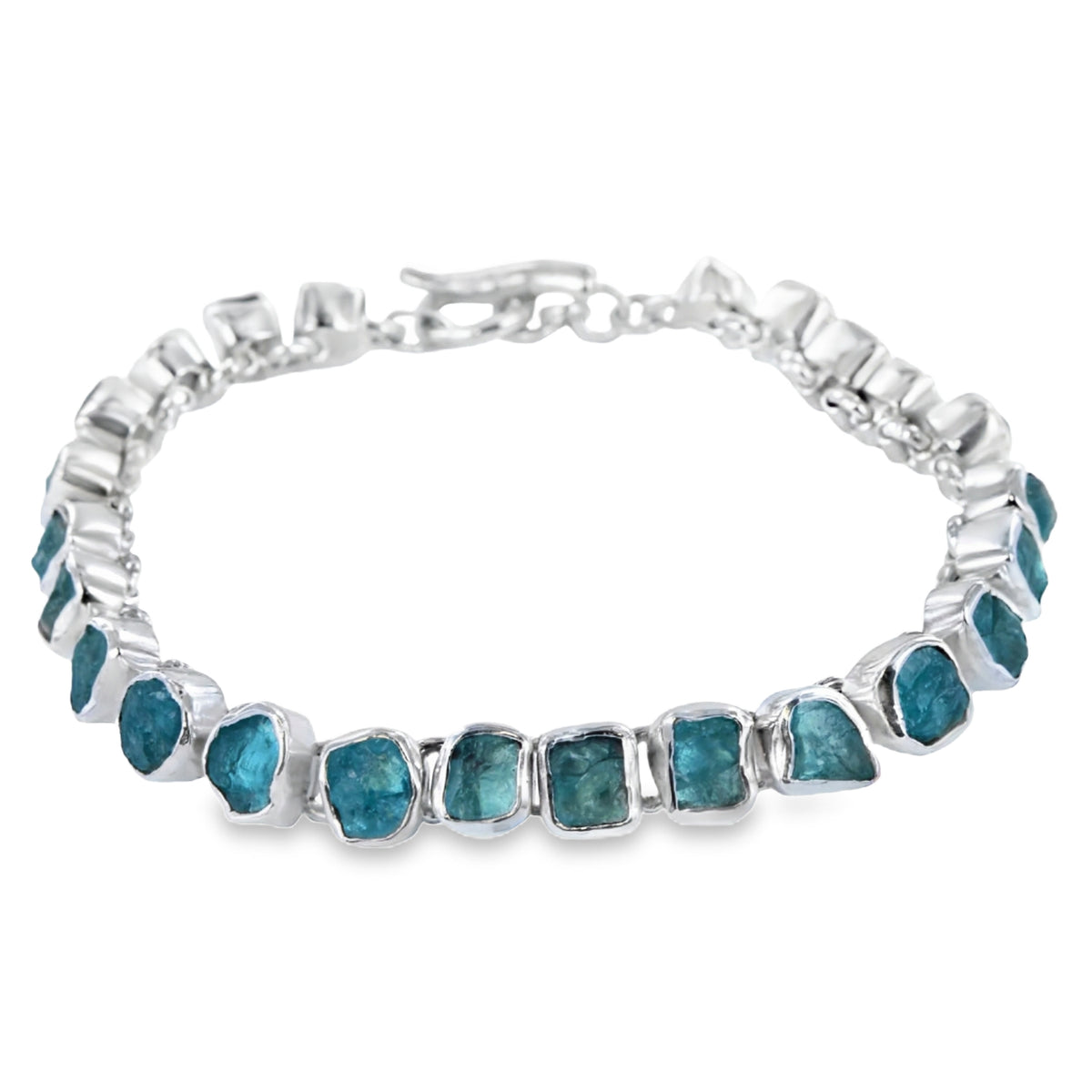 Rough cut apatite stones are set in sterling silver in irregular shapes, and sit in a continuous style around the wrist. The bracelet is finished with a T bar.
