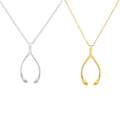 Two wishbone-shaped pendant necklaces on chains, one in silver and one in yellow gold, displayed side by side on a plain white background.