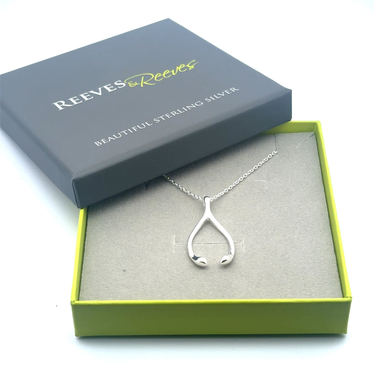 A sterling silver wishbone pendant, sat on a fine silver chain and shown in a Reeves & Reeves gift box.