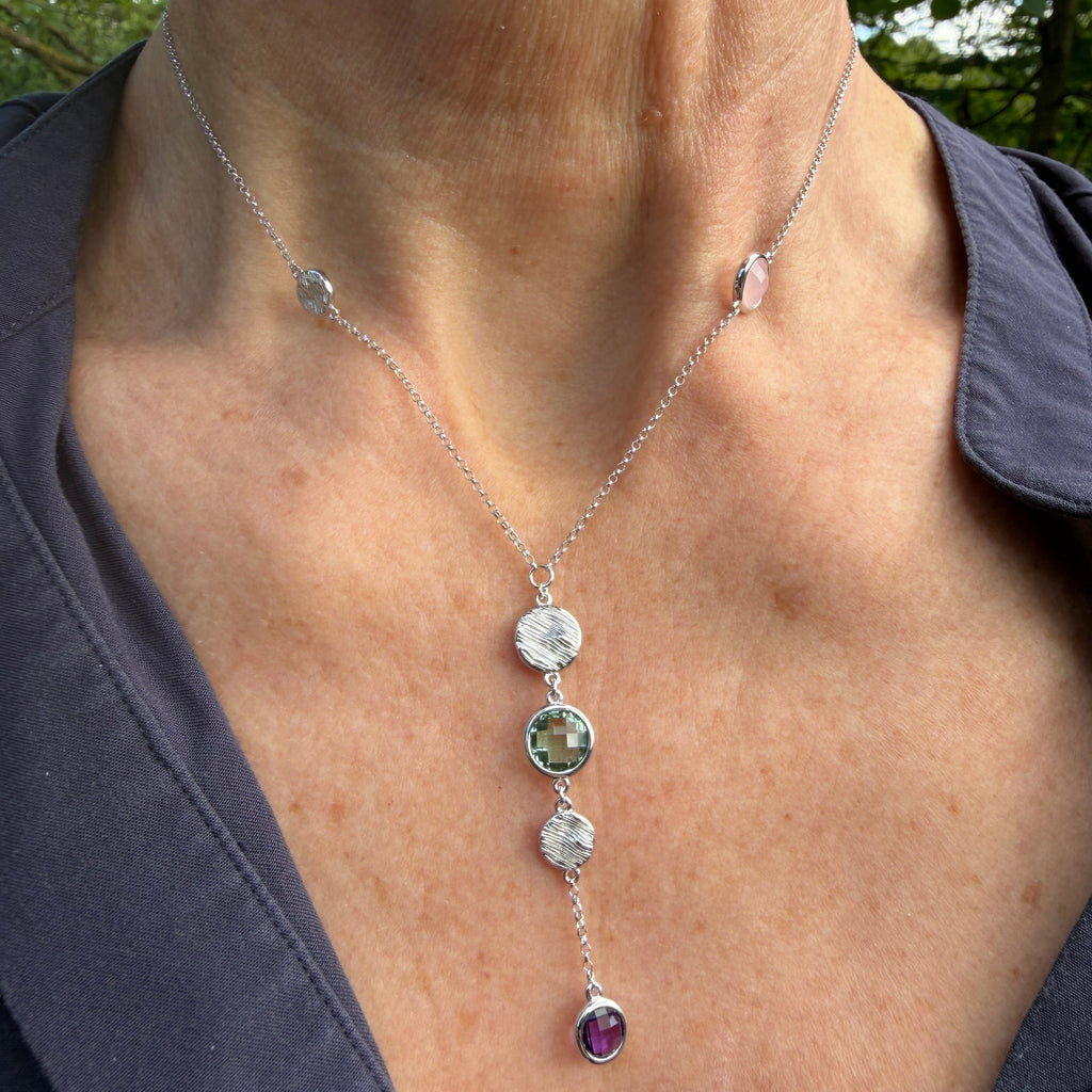 Necklace with gemstone pendants worn by a person outdoors