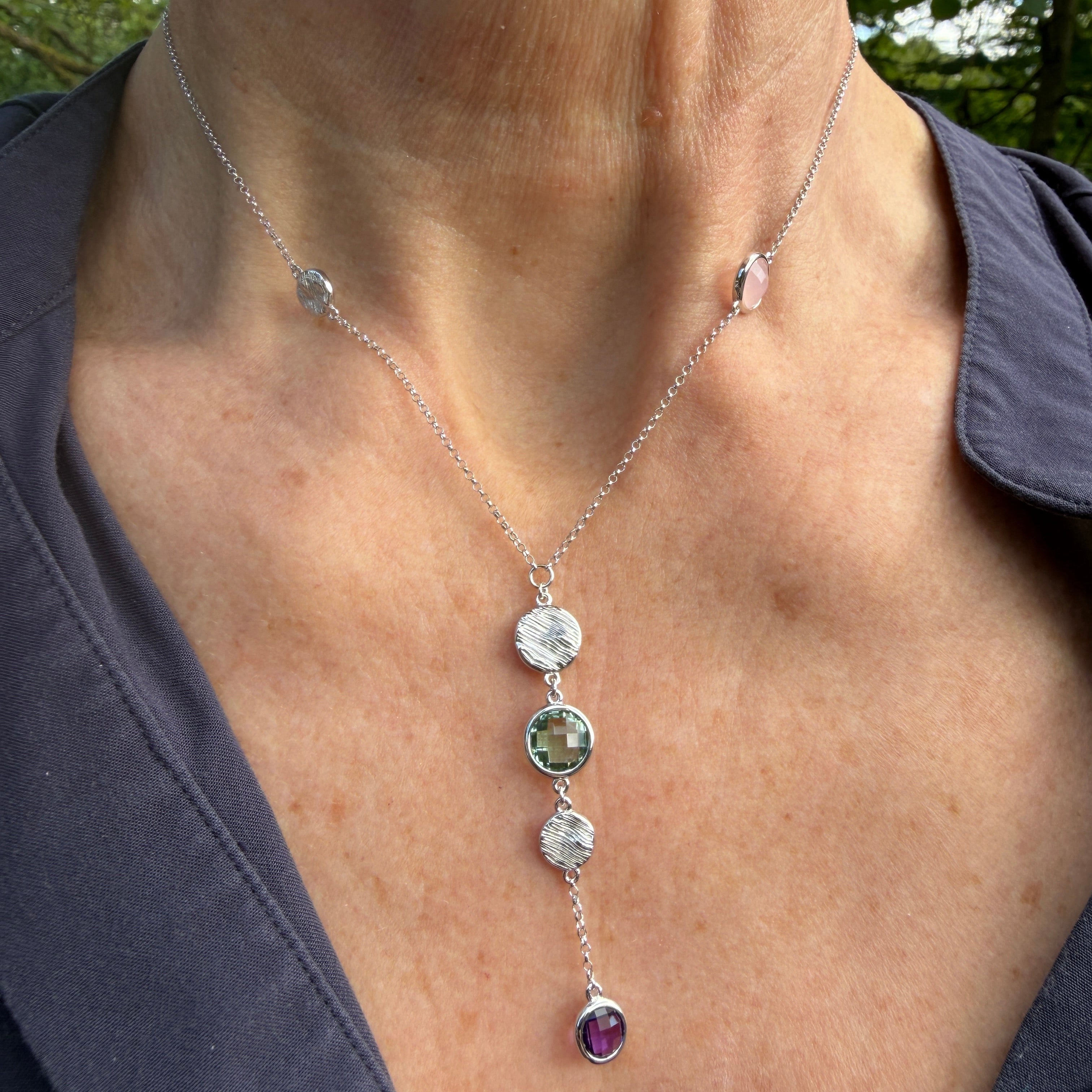 Necklace with gemstone pendants worn by a person outdoors