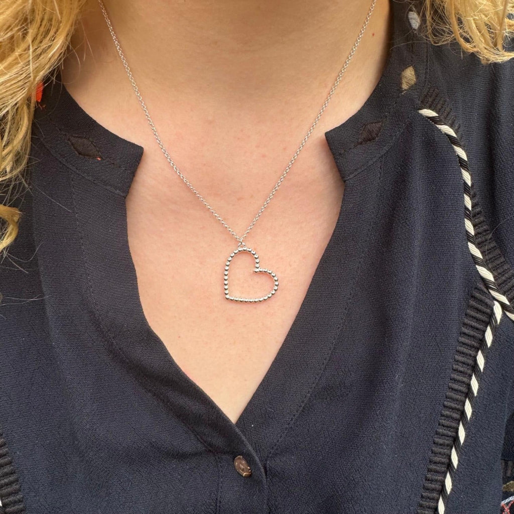 A Sterling Silver Heart silhouette pendant made up of small silver beads. The heart is hung on a silver adjustable chain and worn on a model.