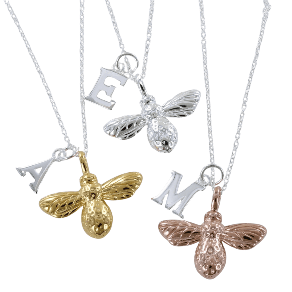 Three Bumble Bee Necklaces, one gold plate, one silver and one rose gold, hanging on silver chains with silver letter charms for personalisation.