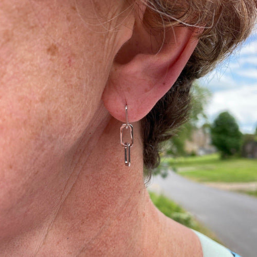 A paperlink chain style drop earring, in sterling silver and shown in a ladies ear.
