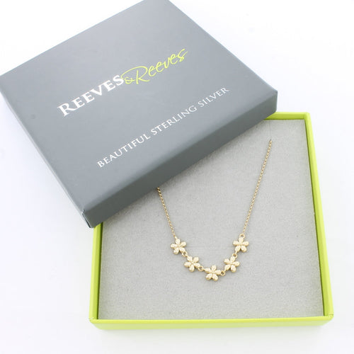 Gold plated chain bracelet with give daisies at the central feature. Shown in a grey and green Reeves & Reeves branded gift box.