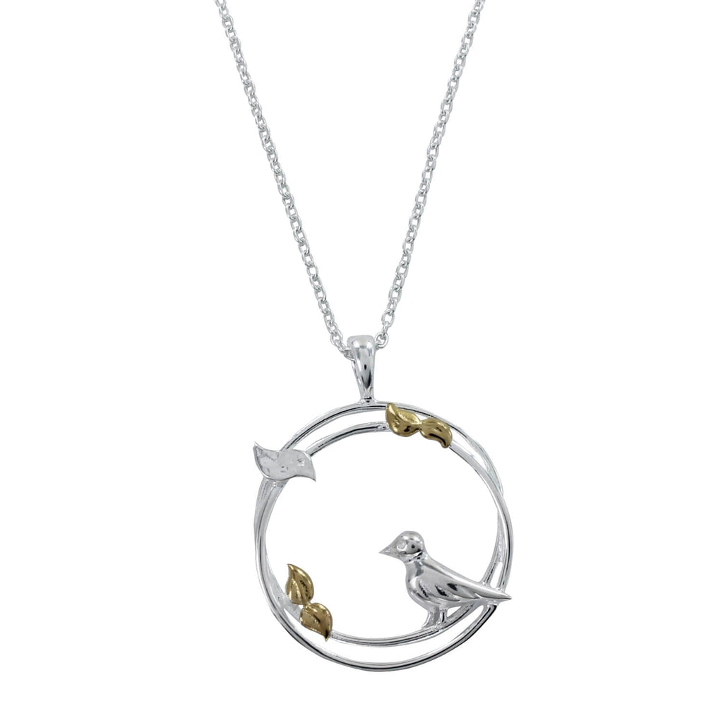A sterling silver circular pendant with a two-ring design featuring birds perched on the edges and leaves with gold plated detail. Hung on a silver adjustable chain.
