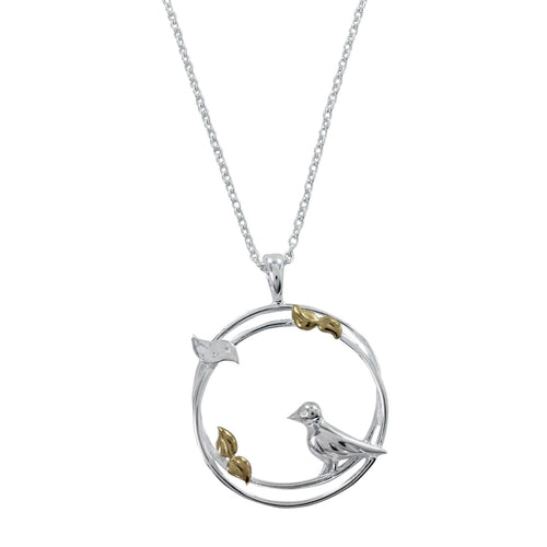 A sterling silver circular pendant with a two-ring design featuring birds perched on the edges and leaves with gold plated detail. Hung on a silver adjustable chain.