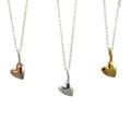 Three Heart Pendants, one rose gold, one silver and one yellow gold, hanging on silver adjustable chains.