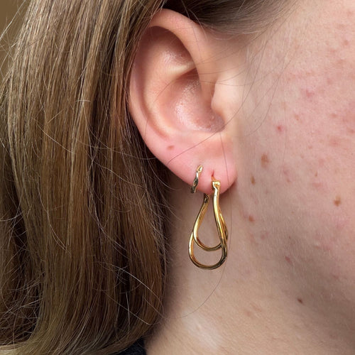 Gold plated double hoop earrings worn in a models ear.