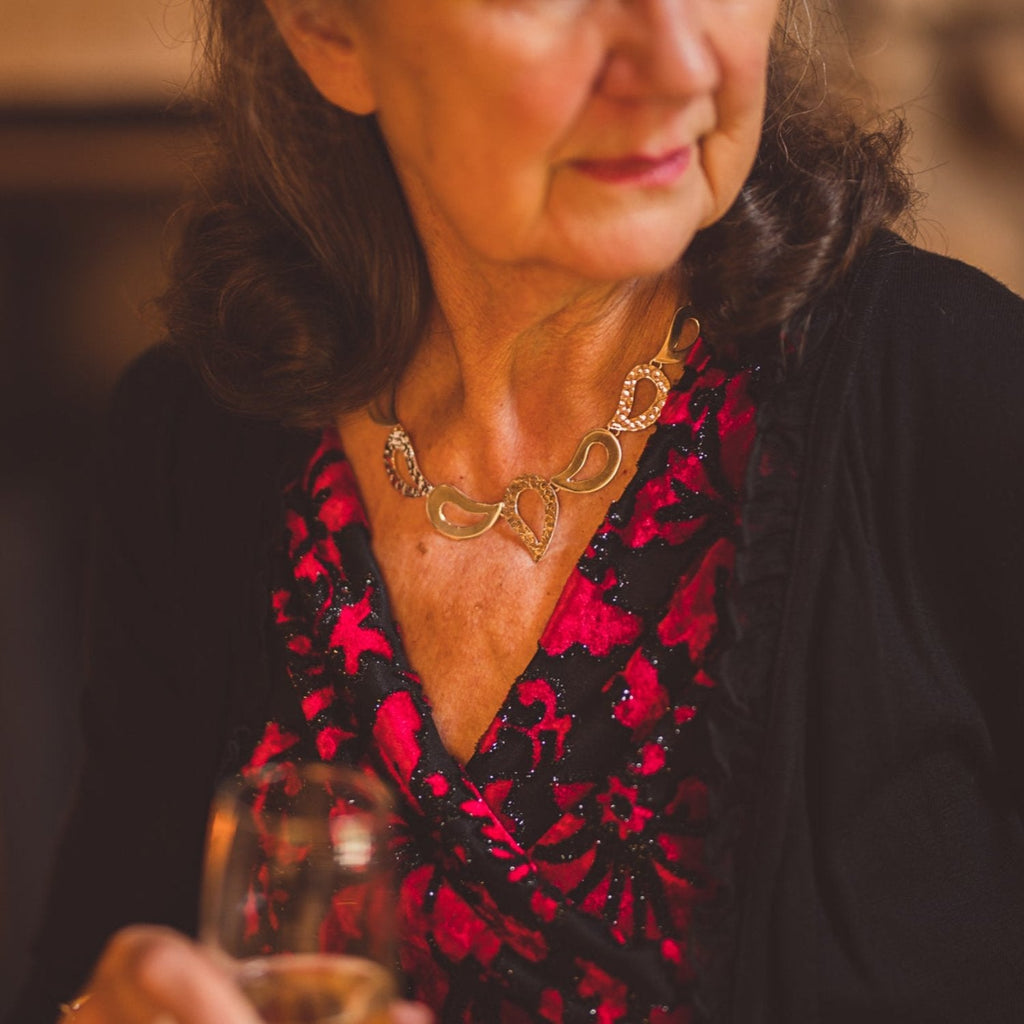 A sterling silver necklace comprised of droplet style silhouettes with both high shine and hammered finish, shown on a model.