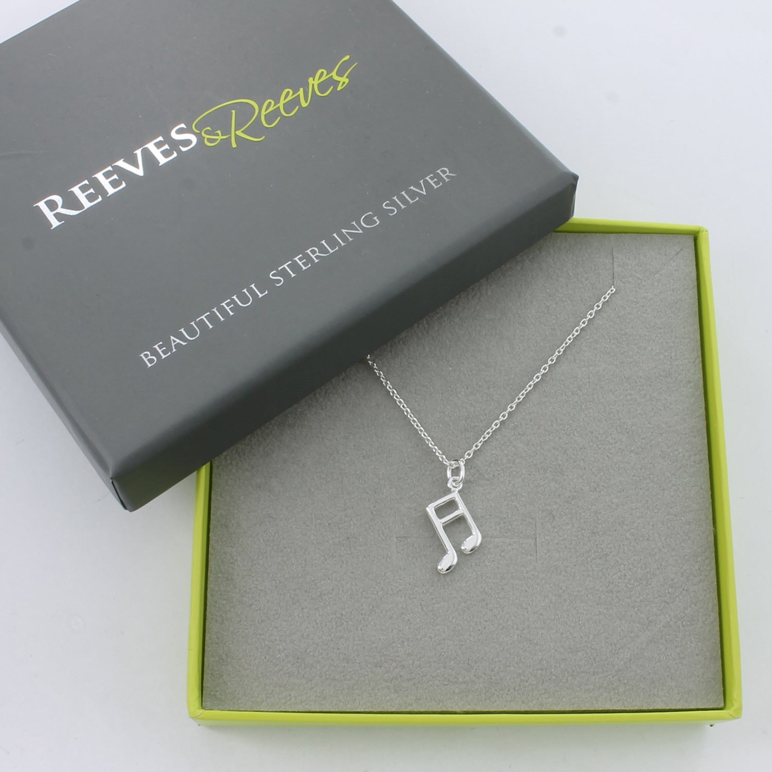 A Sterling Silver Music Note Necklace on a silver chain, shown in a Reeves & Reeves grey and green branded gift box.