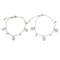 Two bracelets, one gold and one silver, with moon and star charms with white freshwater pearls hanging from the chains.