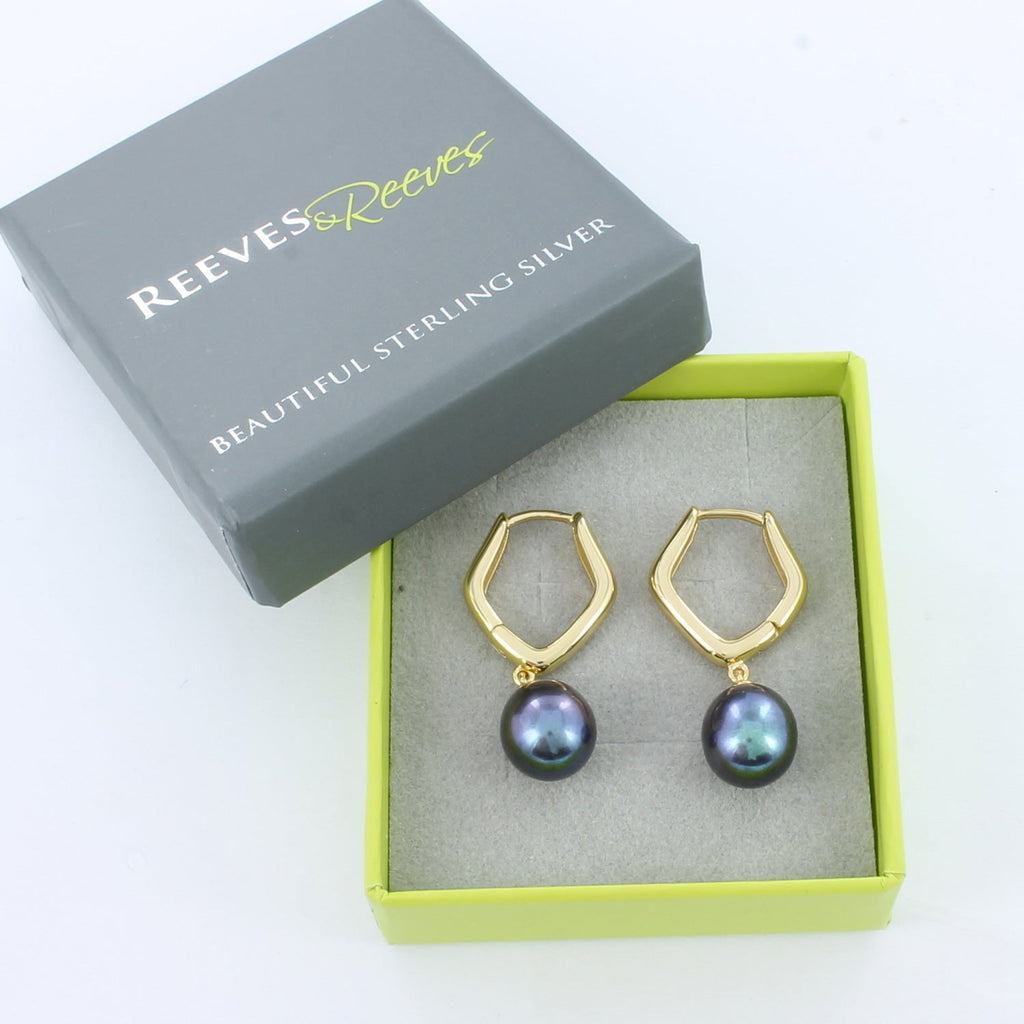 gold plated pentagon shaped huggies with peacock pearl charms hanging from the bottom, shown in a Reeves & Reeves grey and green branded gift box.