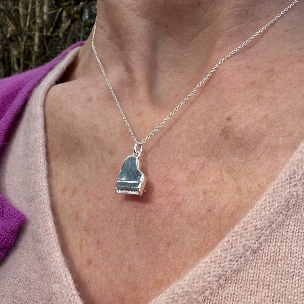 A sterling silver piano pendant, hung on a silver adjustable chain and worn on a model.