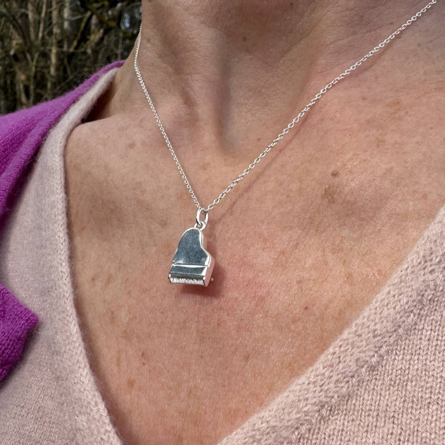 A sterling silver piano pendant, hung on a silver adjustable chain and worn on a model.