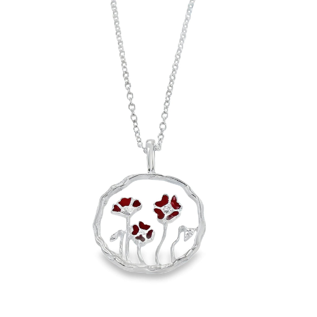 A sterling silver circular pendant with undulated edges. A poppy design sits inside the circle pendant with red enamel detail on the poppies. The design hangs on a silver adjustable chain.