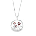 A sterling silver circular pendant with undulated edges. A poppy design sits inside the circle pendant with red enamel detail on the poppies. The design hangs on a silver adjustable chain.