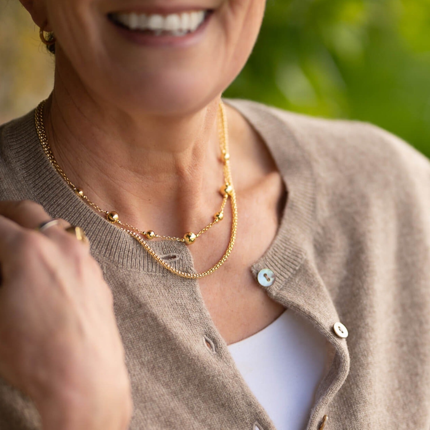 A beaded chain necklace in gold pate, paired with a bobble chain and worn on a model.