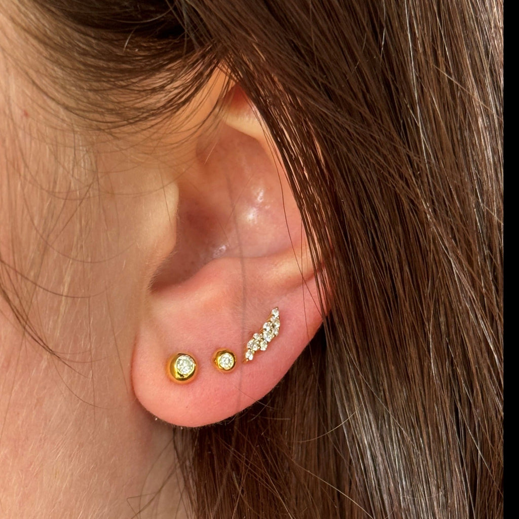 A model wears three stud earrings, two beaded studs with cubic zirconia stones in and a flash cubic zirconia stud further up the ear.