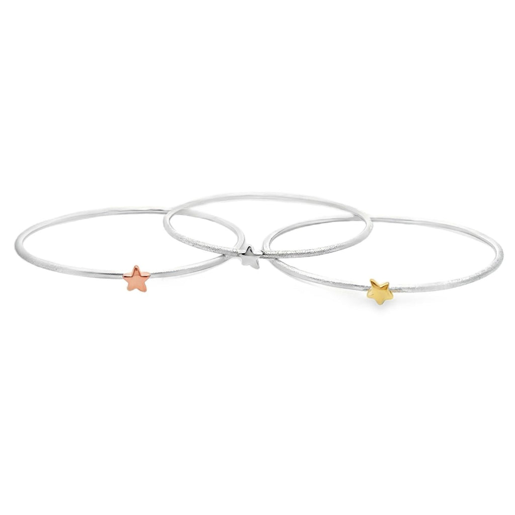 Three thin silver bangles, each with a 3D star charm at the centre, one silver, one 18ct yellow gold and one 18ct rose gold.
