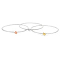 Three thin silver bangles, each with a 3D star charm at the centre, one silver, one 18ct yellow gold and one 18ct rose gold.