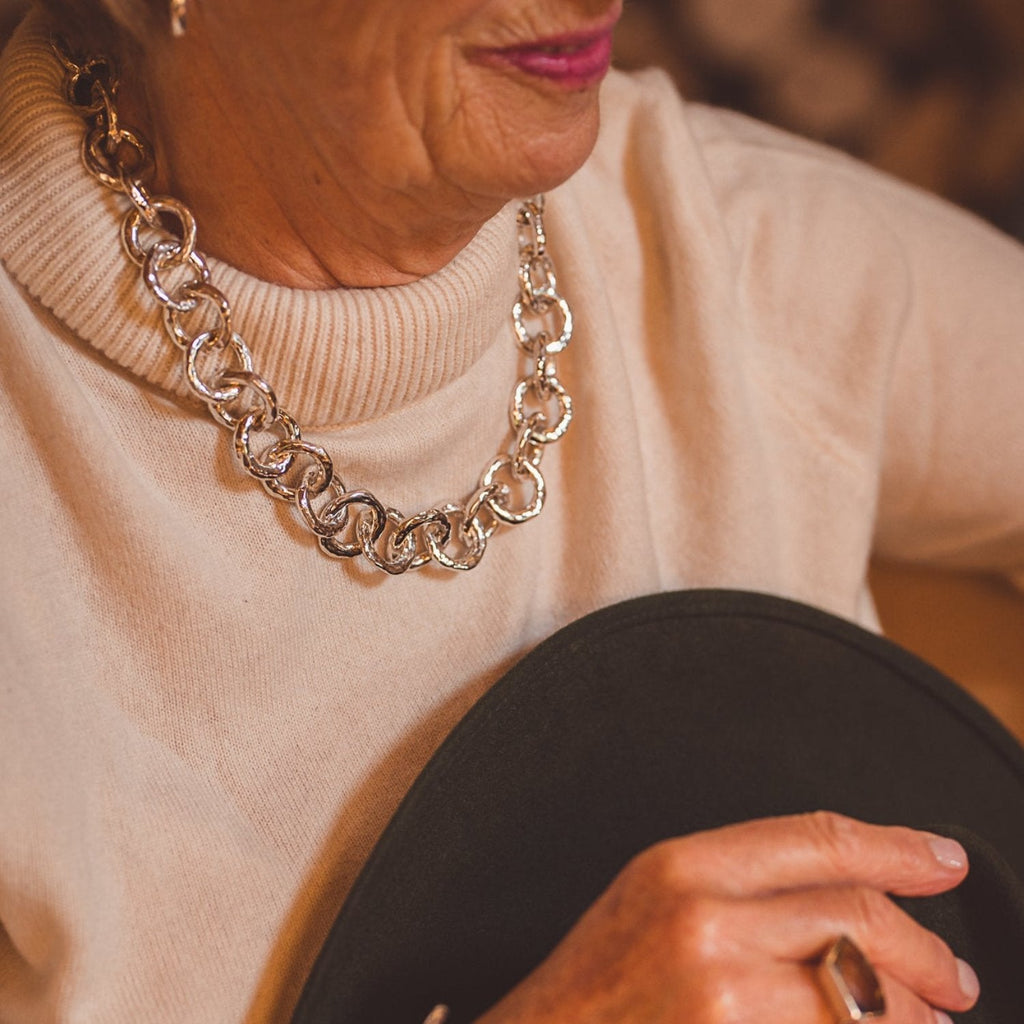 A statement necklace, comprised of hammered style circles, all interlinked around the neck. Worn on a model.
