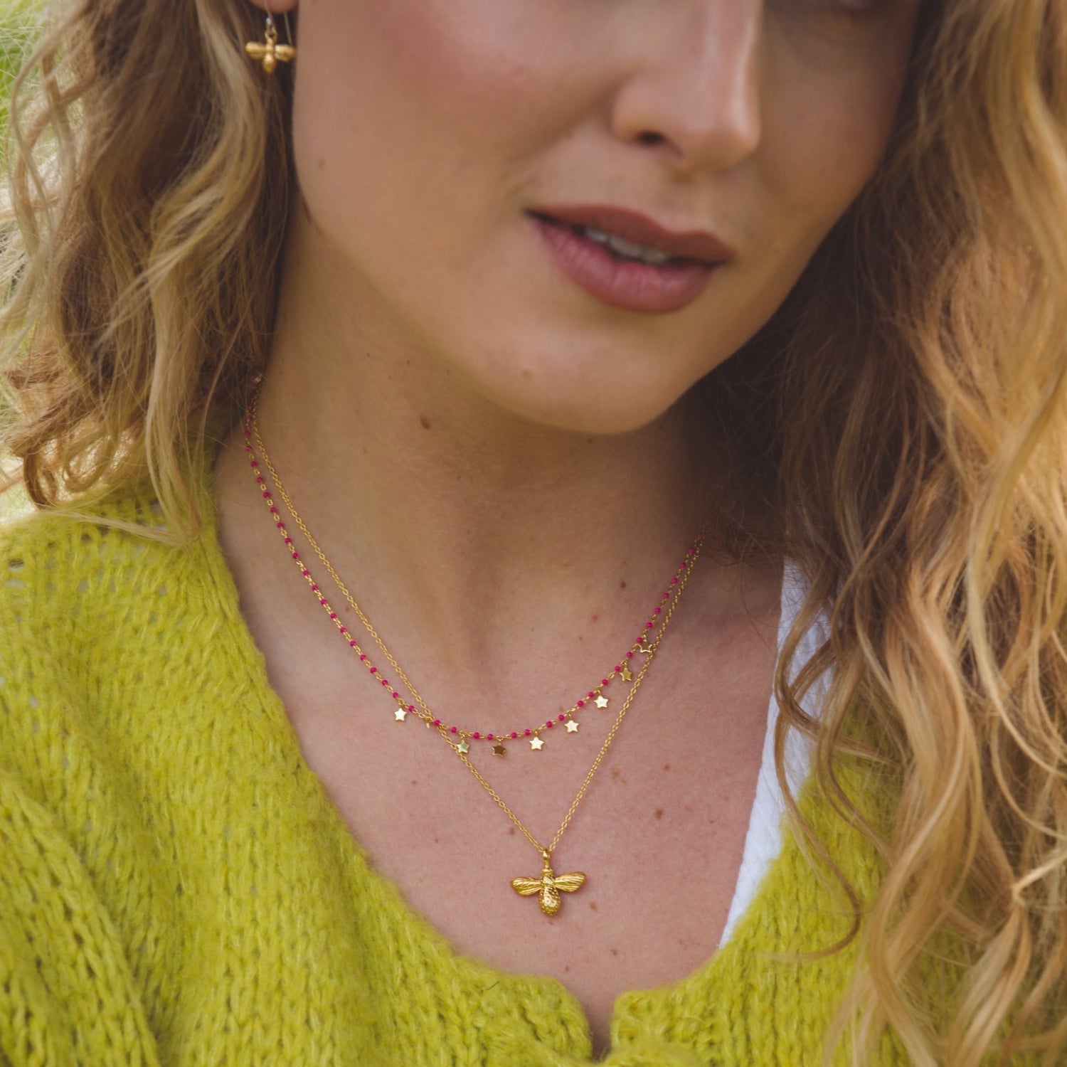 Silver and gold plated pink enamel bead necklace with star charms. Layered with a gold plated bumble bee necklace and shown on a models neck.