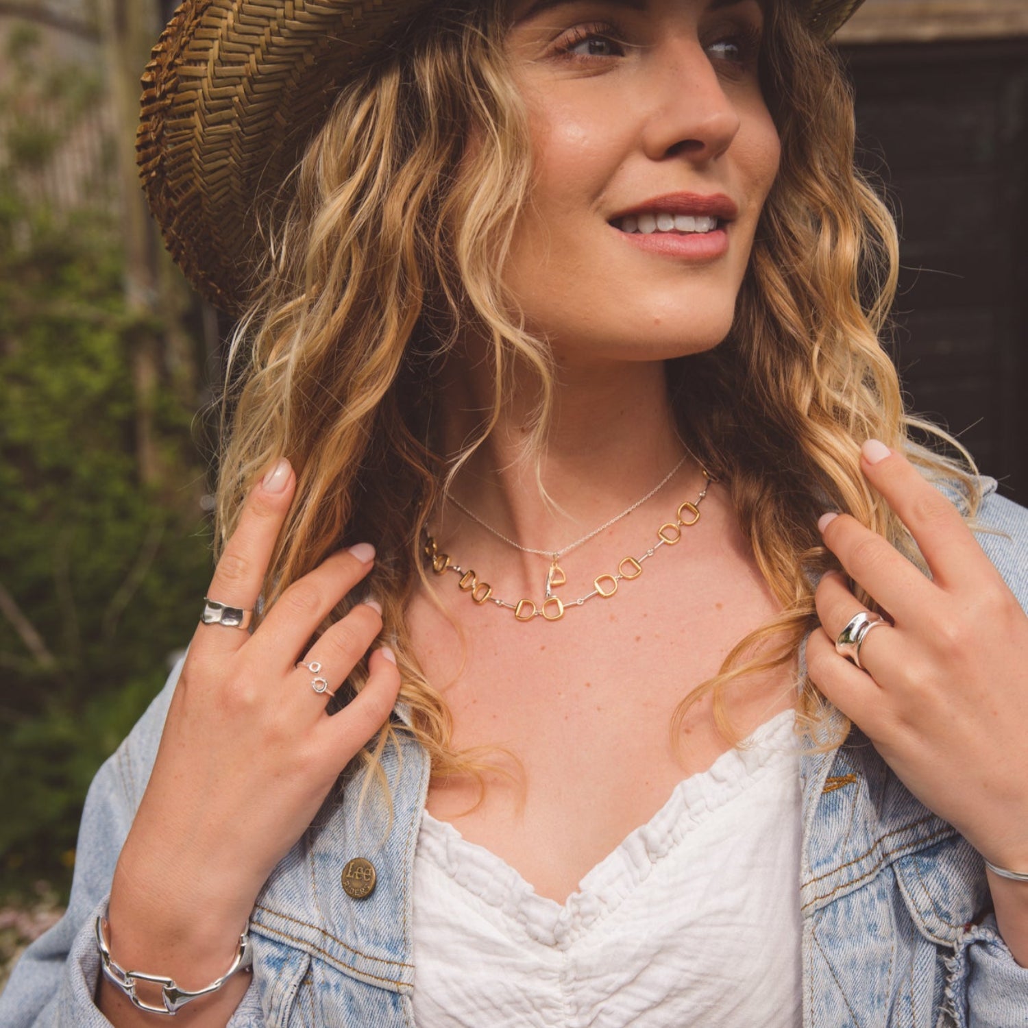 A continuous snaffle necklace with gold plating, worn on a model and layered with another equestrian necklace.