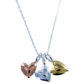 Necklace with three heart-shaped pendants in silver, rose gold, and yellow gold, hanging together on a silver chain.