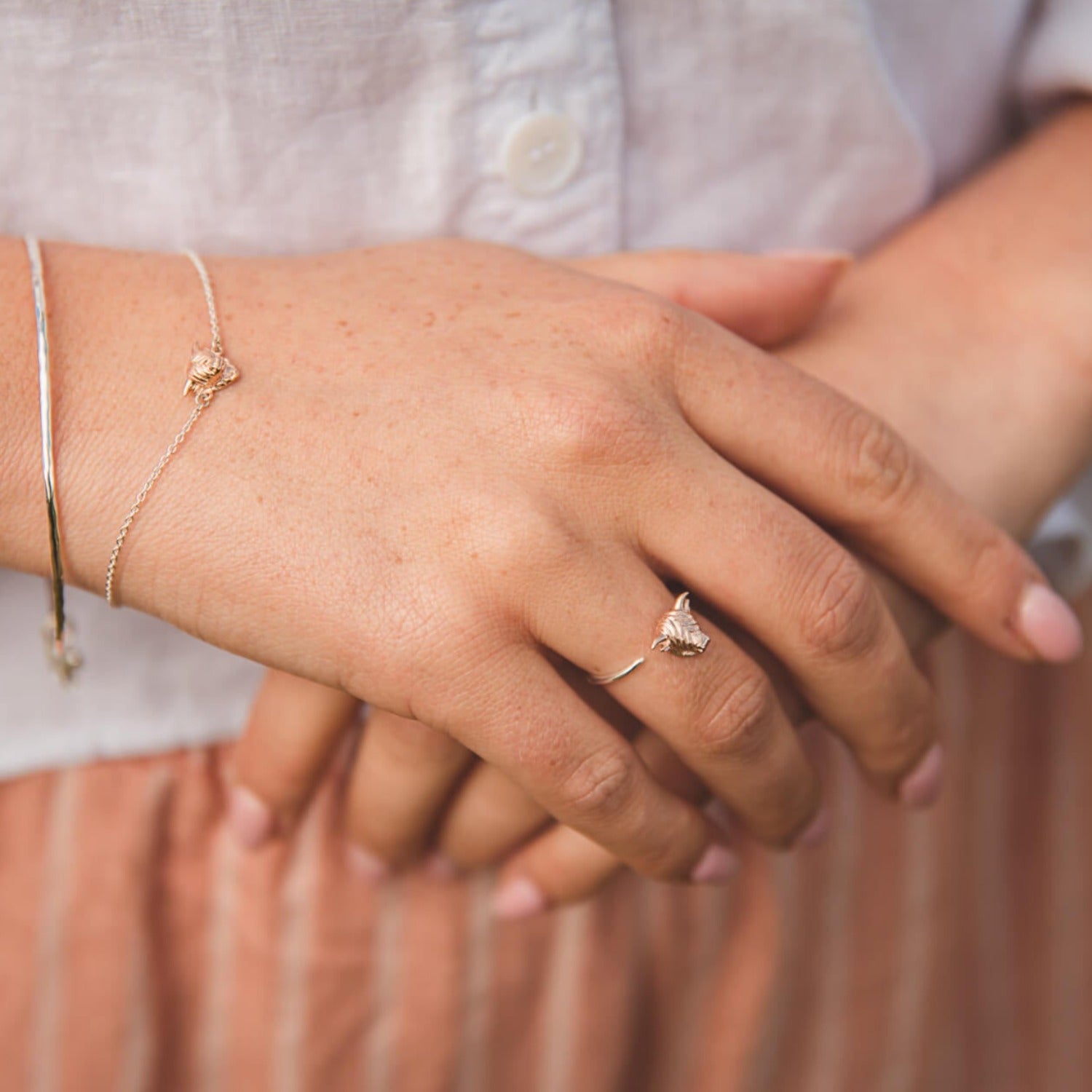 Sterling silver fine band ring with a highland cow face at one end, worn on a ladies finger with the matching bracelet.