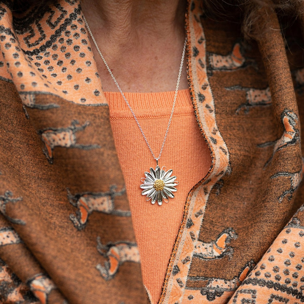 A sterling silver large daisy necklace, with an 18ct gold plate centre and hung on a silver adjustable chain. Worn on a model.