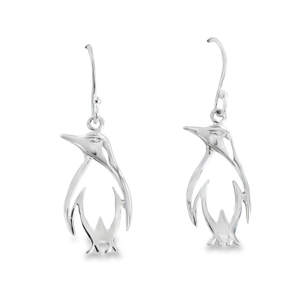 A pair of Penguin silhouette drop earrings, hanging on silver hooks.