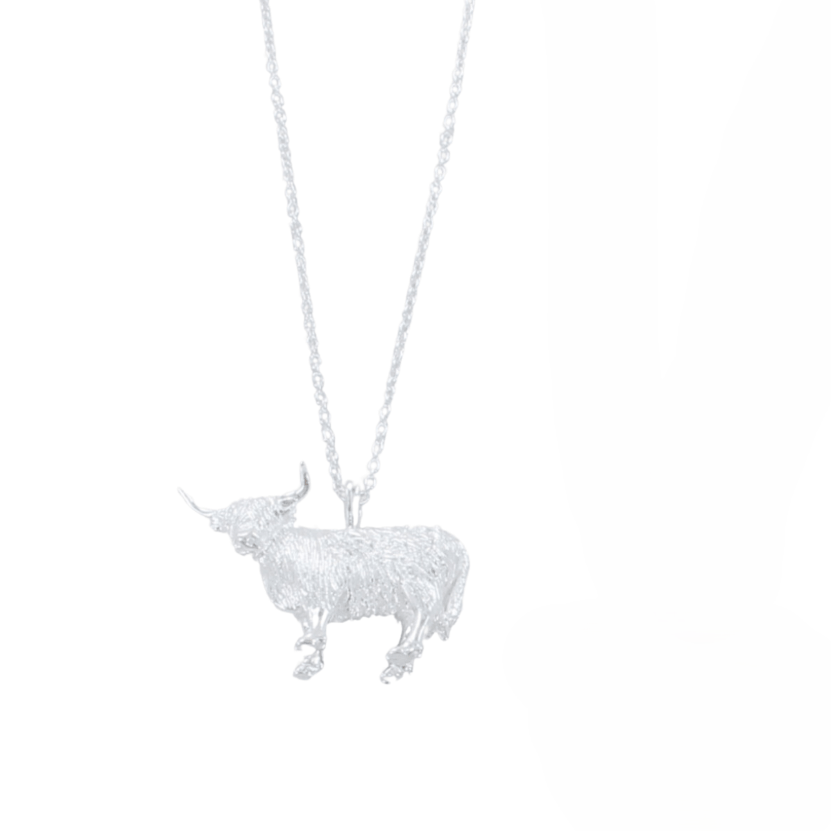 Silver Highland Cow pendant necklace hanging on a silver chain.