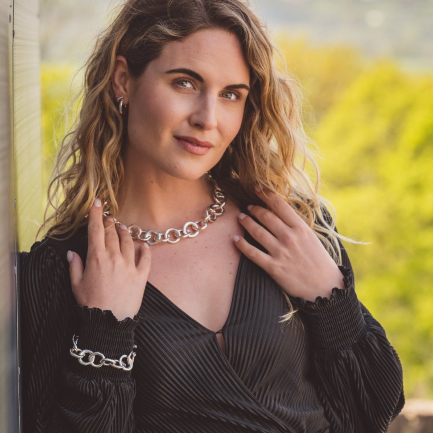 A sterling silver necklace comprising of solid undulated edged circles, interlinked in a continuous motion around the neck and worn on a model with the matching bracelet.