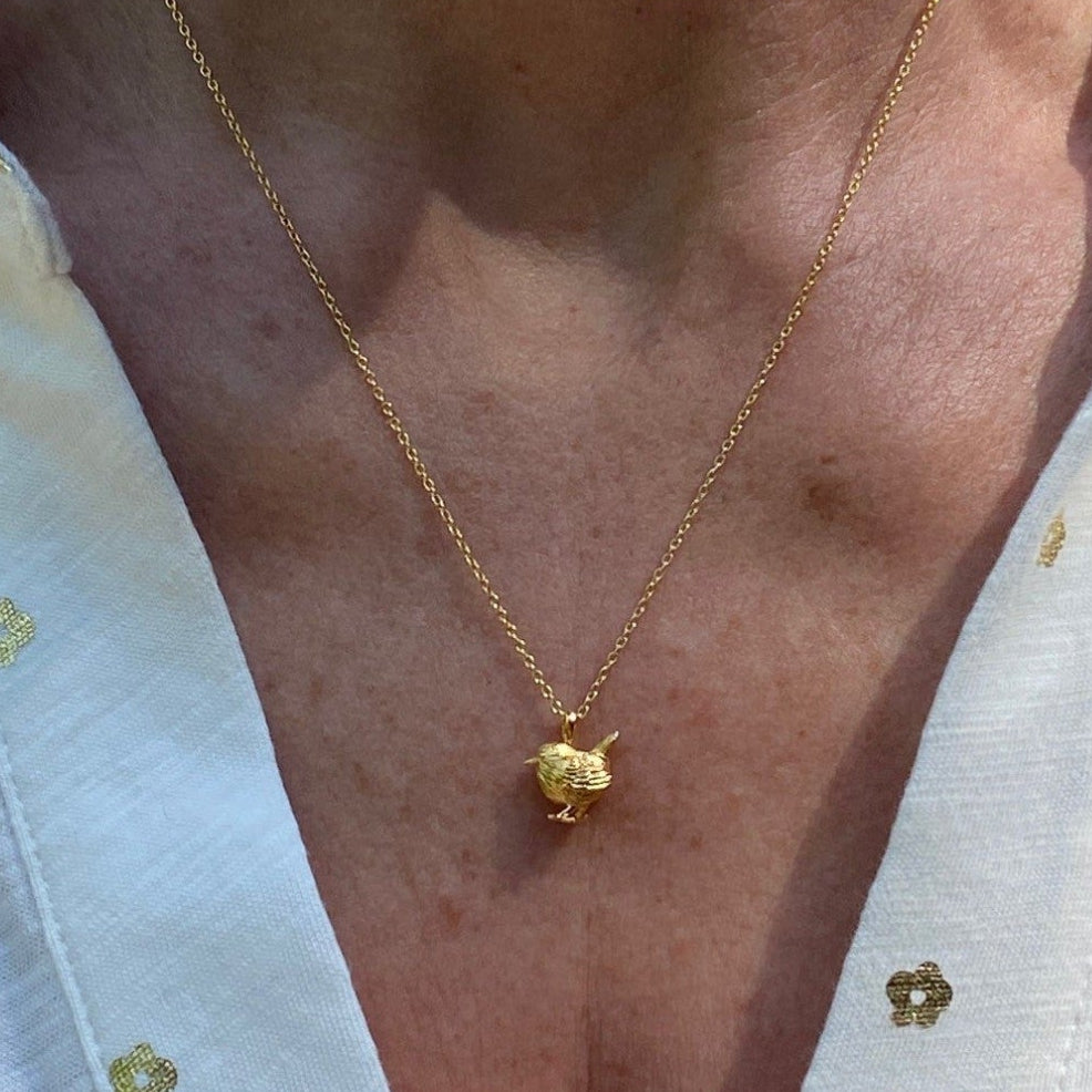 Gold pated Wren Necklace on a gold chain, worn on a model with a v neck blouse. Nature inspired gift for her.
