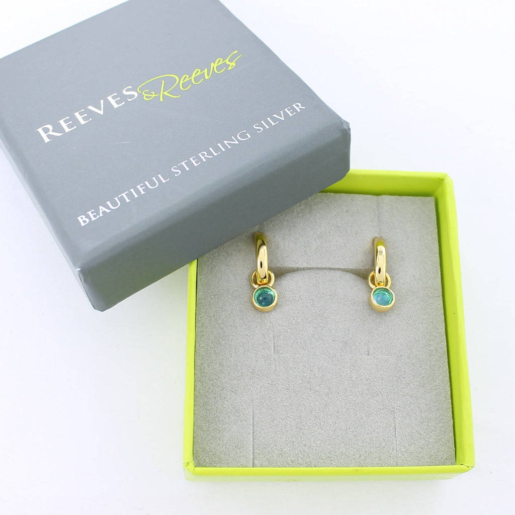 Gold plate hoop earrings with blue gemstones, shown in a Reeves & Reeves grey and green branded gift box.