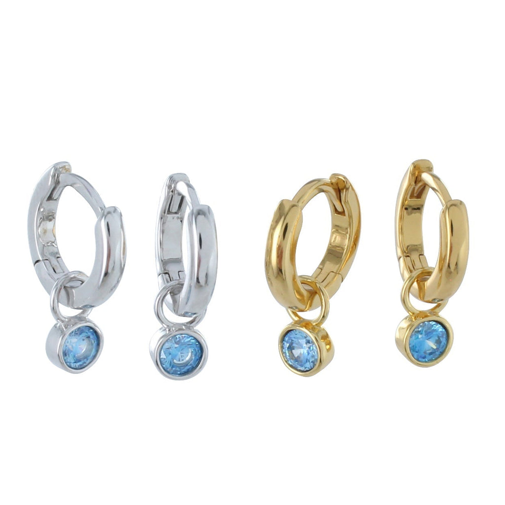 Two pairs of hoop earrings, one silver and one gold plate, with blue gemstone charms hanging from each hoop.