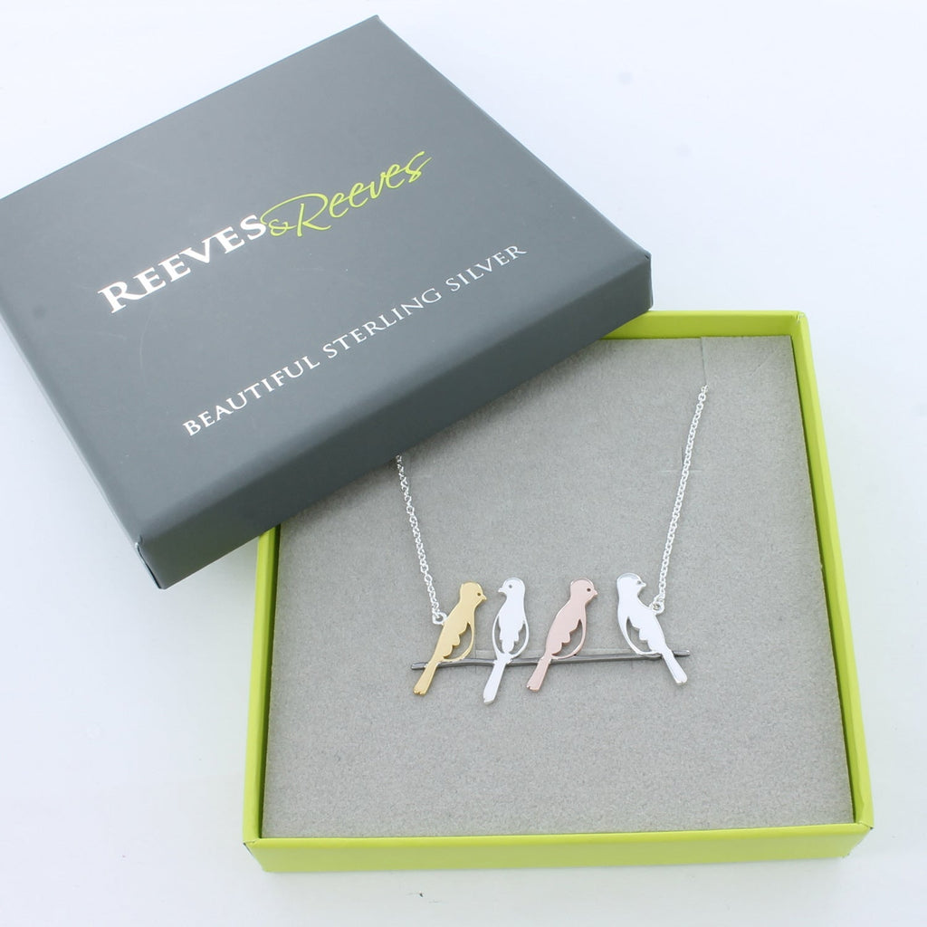 A sterling silver bird necklace, with four bird silhouettes in sterling silver and 18ct rose and yellow gold plate, sat on a branch and sitting centrally on a fine silver chain. Shown in a Reeves & Reeves gift box.