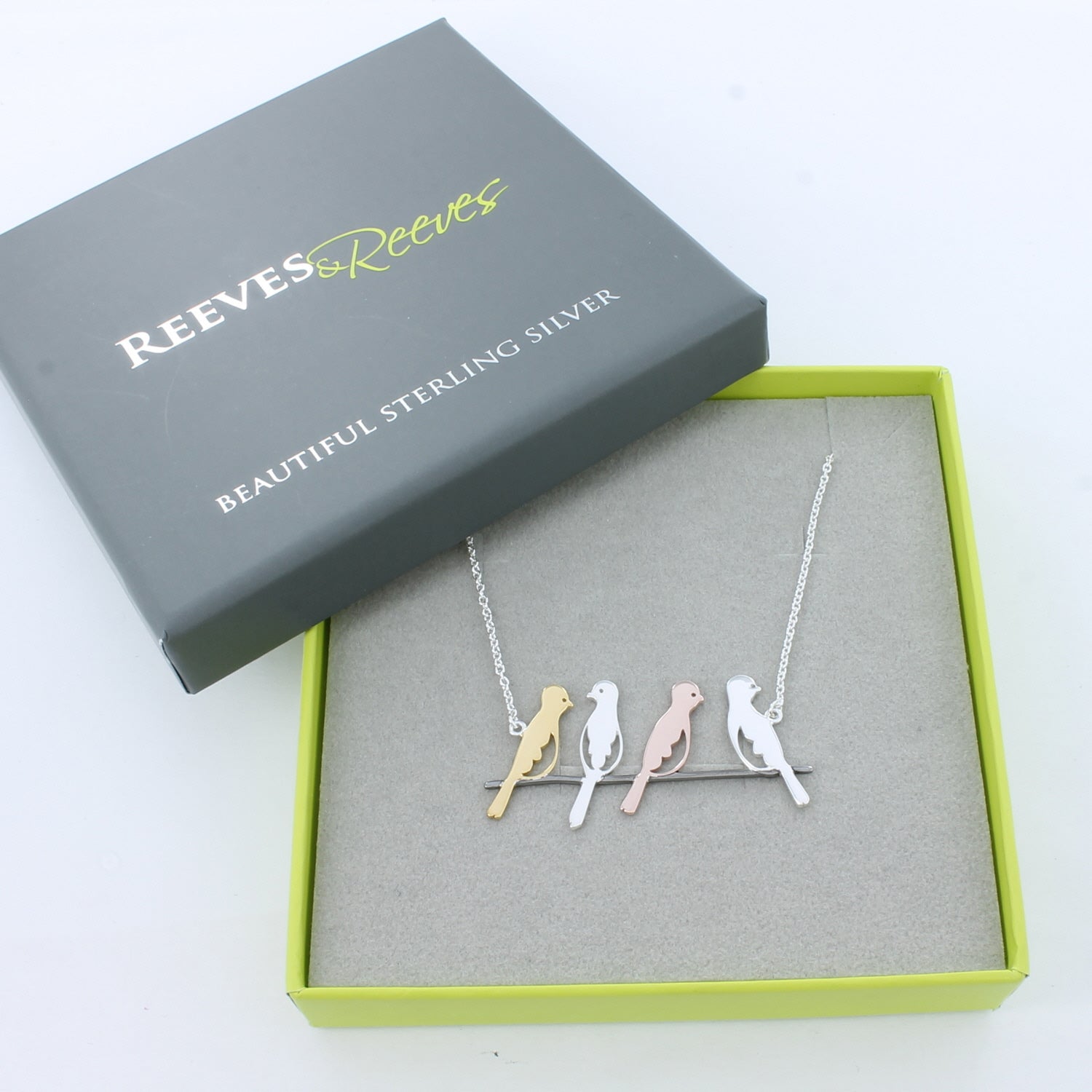 A sterling silver bird necklace, with four bird silhouettes in sterling silver and 18ct rose and yellow gold plate, sat on a branch and sitting centrally on a fine silver chain. Shown in a Reeves & Reeves gift box.